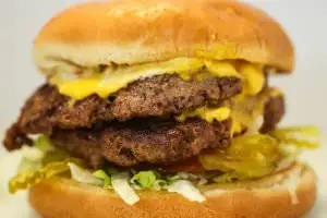 Two (1/2 lb.) patties topped with american cheese, bottomed with lettuce, tomatoes, onions, and pickles. Your choice of condiments.