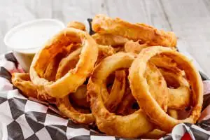 Basket of onion rings served with ranch dressing.