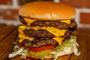 Three (1/2 lb.) patties topped with american cheese, bottomed with lettuce, tomatoes, onions, and pickles. Your choice of condiments.