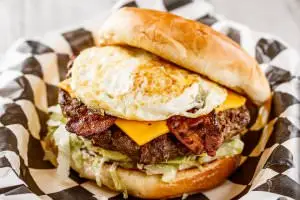 One (1/2 lb.) patty served with 2 slices of bacon, American cheese and a fried egg, bottomed with lettuce, tomatoes, onions, and pickles. Your choice of condiments.